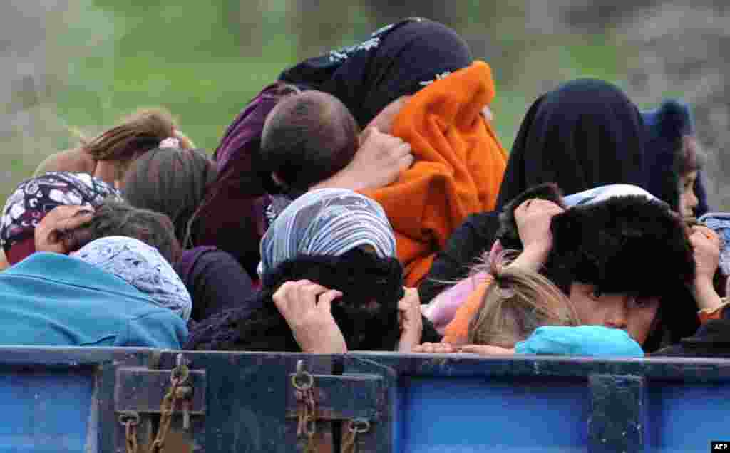 Syrian refugees hide their faces as they arrive near the border between Syria and Turkey at Reyhanli in Antakya. (AFP)