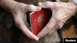Старый паспорт советского образца в руках у пожилого человека.