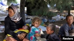 Iraq - A displaced family from the minority Yazidi sect, fleeing the violence in the Iraqi town of Sinjar, waits for food while resting at the Iraqi-Syrian border crossing in Fishkhabour, Dohuk province August 13, 2014