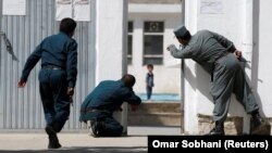 Afghan policemen try to rescue a child after an attack on a Shi'ite Muslim mosque in Kabul on August 25.