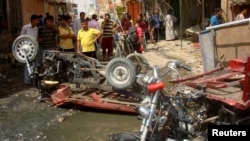 Residents of Diwaniya, Iraq, inspect damaged vehicles at the site of a bomb attack that targeted Shi'ite Muslims earlier this month. 