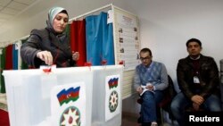 A woman casts her vote during the presidential elections at a polling station in Baku, October 9, 2013