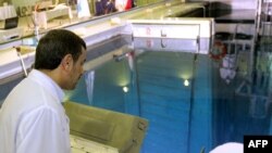 Iranian President Mahmud Ahmadinejad looks at a metal-encased rod with enriched nuclear fuel as it is inserted into a reactor in Tehran. (file photo)