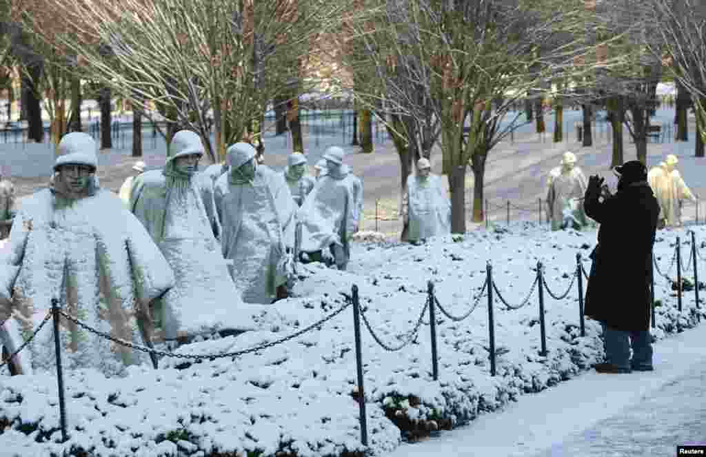 A man photographs the Korean War Veterans Memorial under a layer of snow in Washington, D.C..
