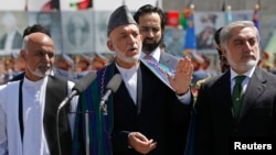 Afghan President Hamid Karzai (center) speaks during celebrations to commemorate Afghanistan's 95th anniversary of independence as he is flanked by presidential candidates Abdullah Abdullah (right) and Ashraf Ghani in Kabul on August 19.