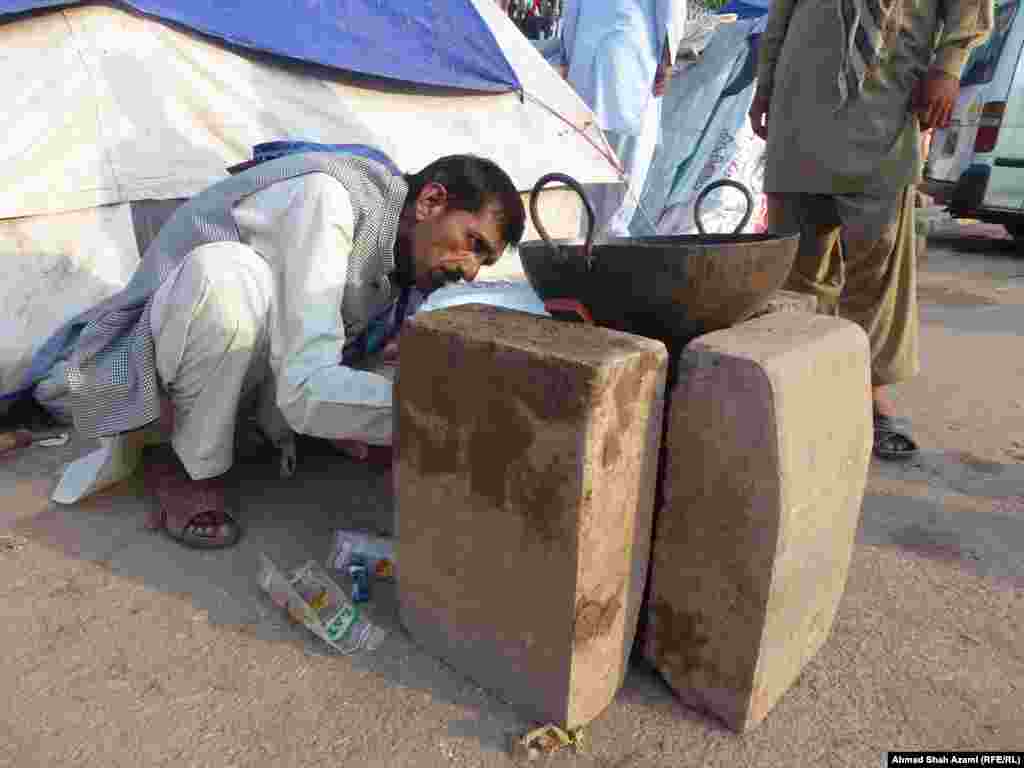 A man prepares a fire at his makeshift stove. 