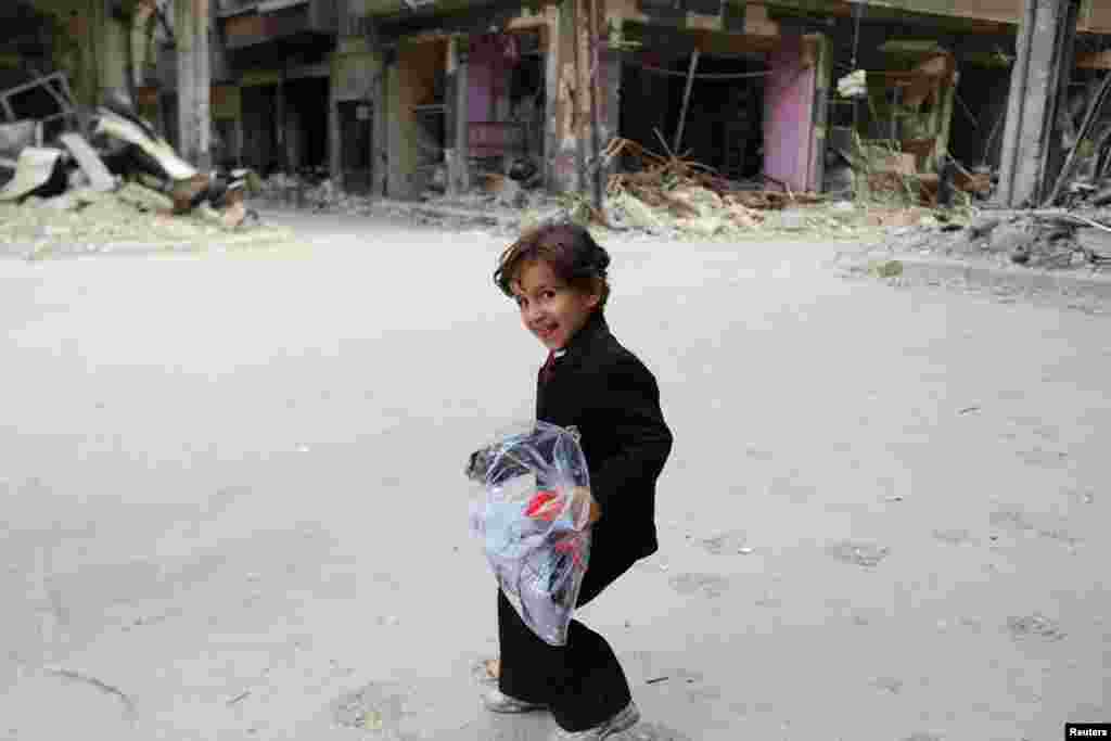 پسربچه&zwnj;ای با کیسه&zwnj;ای از لباس&zwnj;های نو در روز عید فطر. حومه دمشق، ۱۵ ژوئیه ۲۰۱۵