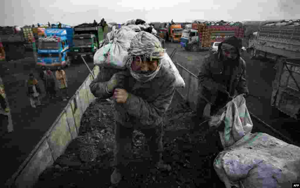 A man loads a sack of coal from Samangan Province onto a truck for transport to Pakistan on the outskirts of Kabul. (AFP/Johannes Eisele)