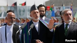 Afghan President Hamid Karzai (C) speaks during celebrations to commemorate Afghanistan's 95th anniversary of independence as he is flanked by presidential candidates Abdullah Abdullah (R) and Ashraf Ghani in Kabul, August 19, 2014