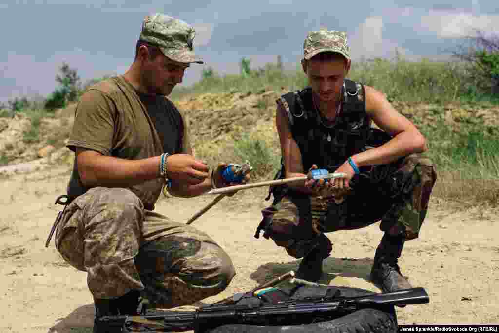 Soldiers attach grenades to sticks during a training exercise on disarming booby traps.