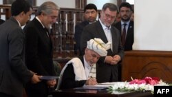Afghan President Ashraf Ghani (C) signs a peace deal with Afghan warlord Gulbuddin Hekmatyar at the Presidential Palace in Kabul on September 29.