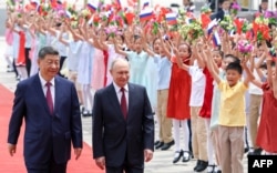 Сотні дітей з прапорцями вітають очільника Росії Путіна під чс церемонії зустрічі його головою Китаю Сі Цзіньпіном. Біля Будинку народних зібрань у Пекіні, КНР. 20 травня 2026 року
