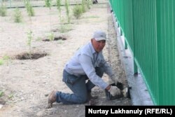 Марат Жаканов красит забор нового парка в Баршатасе