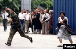 Босненски войник и цивилна жена - и двамата с малки деца на ръце, тичат през пресечка, набелязана от сръбски снайперист, по време на обсадата на Сараево.