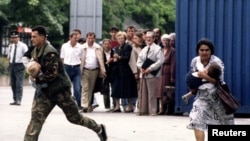 Građani trče preko raskrižja koje je ciljao srpski snajperist, oboje noseći malu djecu u naručju 29. juna 1995. u Sarajevu.