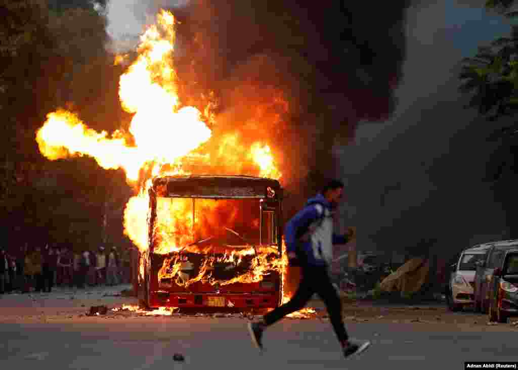 A man runs past a burning bus that was set on fire by demonstrators during a protest in New Delhi on December 15.