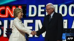 Hillary Clinton dhe Bernie Sanders duke u përshëndetur në fillim të debatit