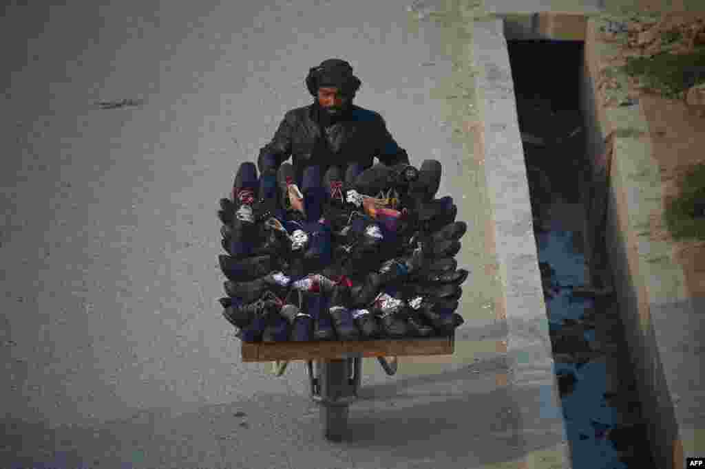 An Afghan vendor pushes a wheelbarrow as he transports secondhand shoes in Mazar-e Sharif. (AFP/Farshad Usyan)