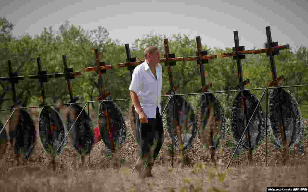 A man walks past a funeral ceremony for 30 civilians who were exhumed from a mass grave a week before near the village of Irmino, not far from Pervomaysk in Ukraine&#39;s Luhansk region, on August 31.
