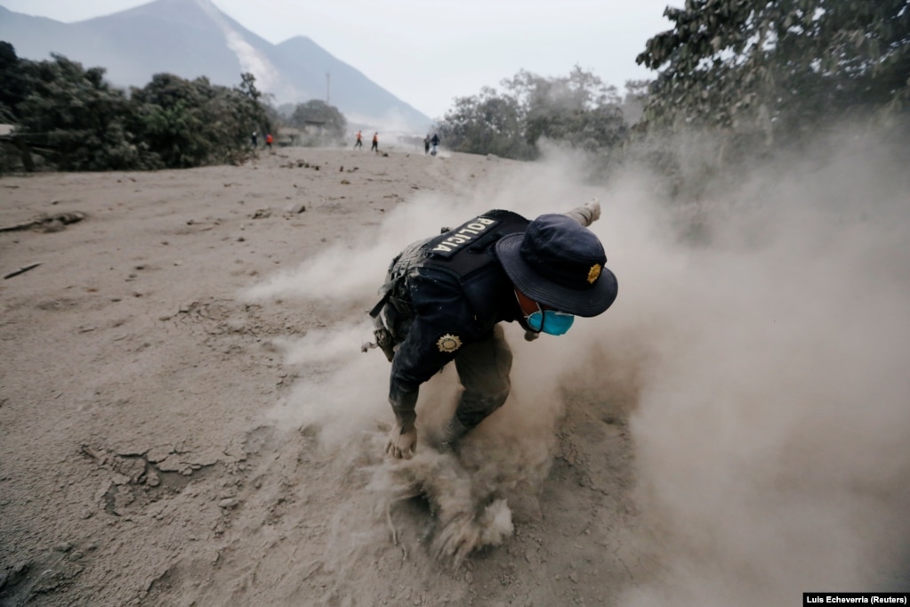 A police officer stumbles while running away after the Fuego volcano spew new pyroclastic flow in the community of San Miguel Los Lotes in Escuintla, Guatemala, on June 4. (Reuters/Luis Echeverria)