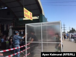 "Кенжехан" базарына келушілер кіреберістегі антисептик бүркіп тұрған орыннан өткен соң, күзетші арнайы құралмен олардың дене қызуын тексереді. Алматы, 3 маусым 2020 жыл.