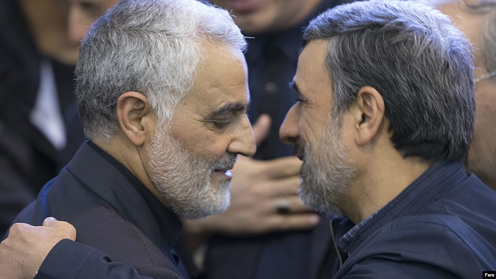 Commander of Quds force, Qassem Soleimani (left) shakes hands with President, Mahmoud Ahmadinejad, in the funeral of his mother, 2013.
