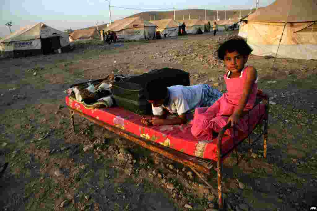 Syrian-Kurdish children sit on a bed at the Quru Gusik refugee camp, 20 kilometers east of the city of Irbil in norther Iraq. Faced with brutal violence and soaring prices, thousands of Syrian Kurds have poured into Iraq&#39;s autonomous Kurdish region, seeking respite from privation and fighting between Kurdish fighters and jihadists. (AFP/Safin Hamed)