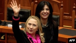 U.S. Secretary of State Hillary Clinton (left) waves after speaking to the Albanian parliament in Tirana, as speaker Josefina Topalli walks beside her.