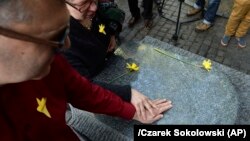 A man touches a monument at an independent ceremony in honor of the fighters of the 1943 Warsaw Ghetto Uprising on its 75th anniversary in Warsaw on April 19.