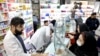 Pharmacists talk with customers at a drugstore in downtown Tehran, February 25, 2020