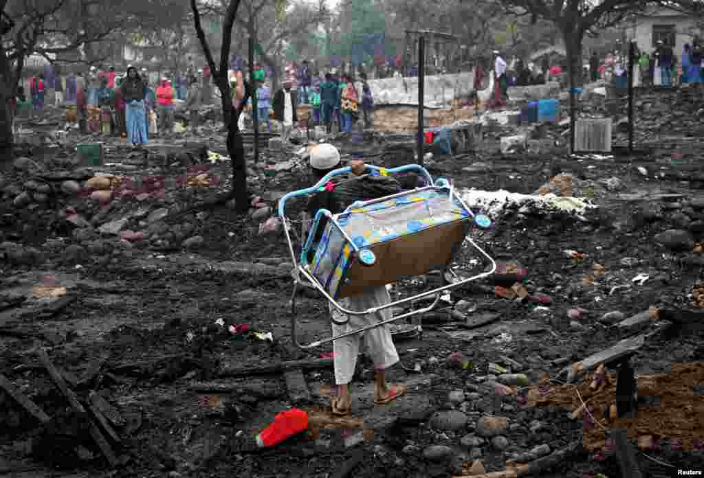 A boy carries his sister's baby bed after his house was burned down in a fire that broke out in a slum area in Jammu, India. (Reuters/Mukesh Gupta)