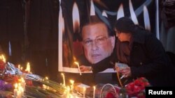 A woman lights a candle next to an image of the governor of Punjab, Salman Taseer, during a candlelight vigil near the site of his assassination in Islamabad.