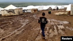 A refugee boy walks through mud at a refugee camp in Atimeh, on the Syrian-Turkish border of the Idlib Governorate.