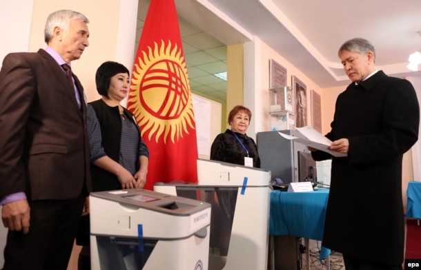 Kyrgyz President Almazbek Atambaev (right) arrives to cast his ballot at a polling station during the referendum on constitutional changes in Bishkek on December 11.
