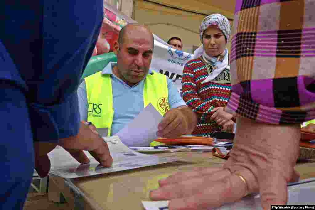 U.S.-based Catholic Relief Services (CRS) and their local partner Caritas Iraq have joined the World Food Program to support the refugees and provide meals. Here a local CRS worker checks documents belonging to some Syrian refugees.