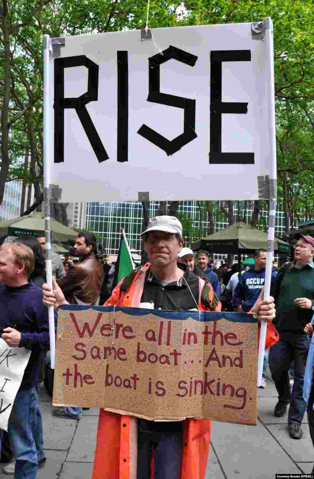 An activist carries a sign warning that America is a sinking ship and calling on its citizens to "rise."