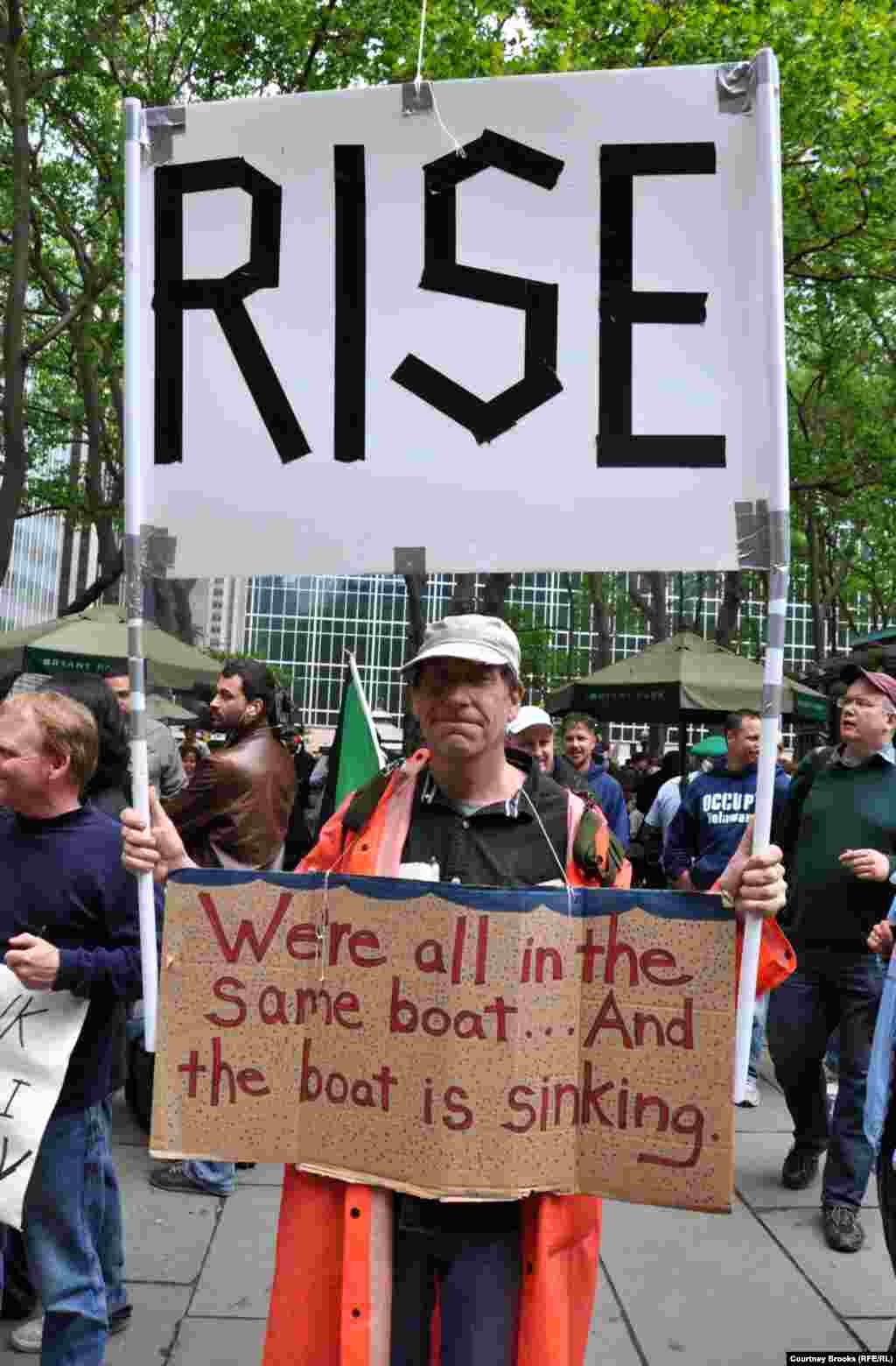 An activist carries a sign warning that America is a sinking ship and calling on its citizens to &quot;rise.&quot;