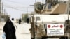 An Iraqi woman walks past a U.S. Marine vehicle on the streets in the restive city of Fallujah in 2007.