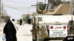 An Iraqi woman walks past a U.S. Marine vehicle on the streets in the restive city of Fallujah in 2007.