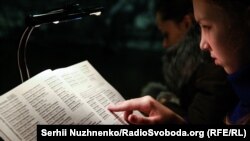 Дівчина шукає у «книгах пам’яті» загиблих від Голодомору прізвища померлих близьких, музей «Меморіал жертв Голодомору» у Києві, фото архівне