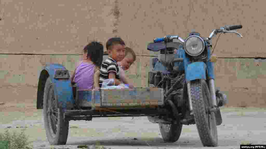 Сельские дети играют в деревянном ящике на прицепе старого мотоцикла.