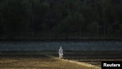 The early morning sun hits a man as he walks across a field near the village of Qandaro in the Pech River Valley of Kunar Province on July 2.