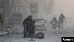 A man in a wheelchair flees with others into the remaining rebel-held areas of Aleppo on December 9.