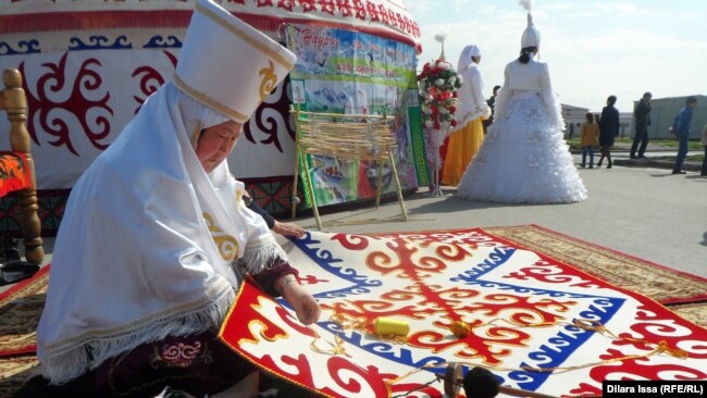 Оралмандар тұратын елдімекендегі Наурыз мейрамы кезінде ұлттық киім киіп, сырмақ тігіп отырған әйел. Көрнекі сурет.