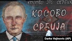 Прохожий в Белграде на фоне графити с надписью: «Косово – это Сербия», август 2019