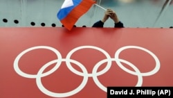 A Russian skating fan holds the country's national flag over the Olympic rings before the start of the men's 10,000-meter speed-skating race at the 2014 Winter Olympics in Sochi.
