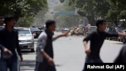 Afghans run from the site of a suicide attack in the center of Kabul on May 9, 