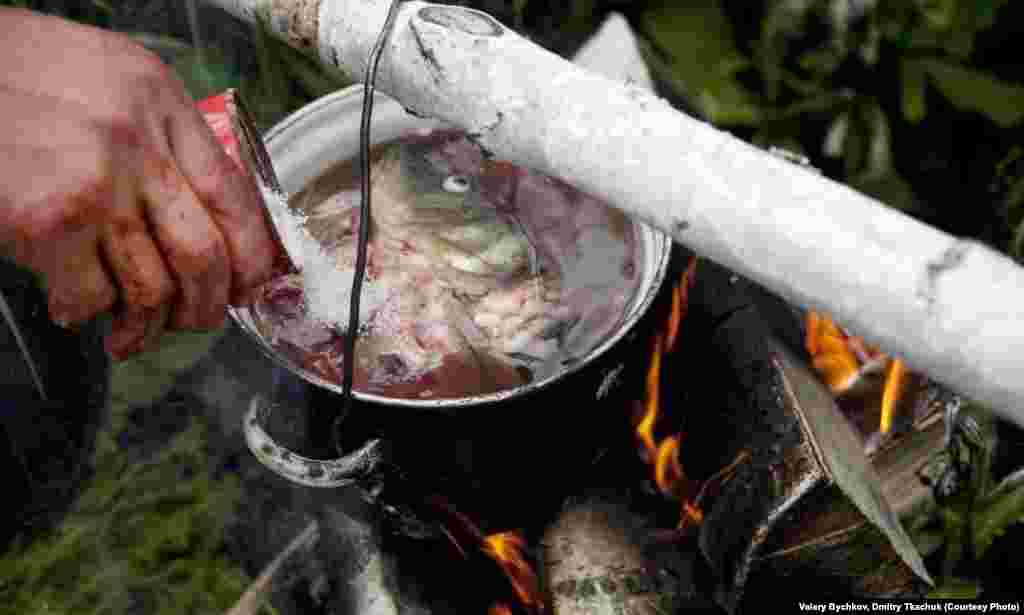 Fish is the most common dish for most villagers. Here, a man cooks fish soup on an open fire.