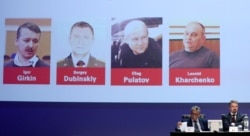 The four suspects in the case are shown on a screen as international investigators present their findings to the media in June last year.