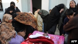 Shi'a mourn beside the body of a blast victim following the overnight suicide bomb attack on a Shi'ite procession in Rawalpindi on November 21-22.